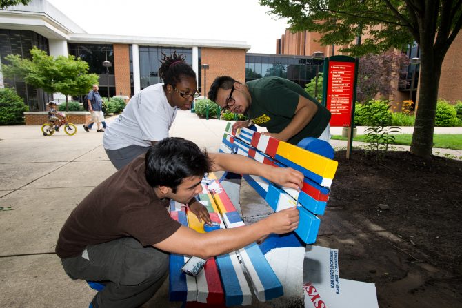 Students of the Hispanic Student Association paint a bench outside SUB 1 at Fairfax Campus.