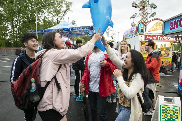 Picture of two students holding a dolphin balloon at carnival, Mason Day 2019, Fairfax Campus.